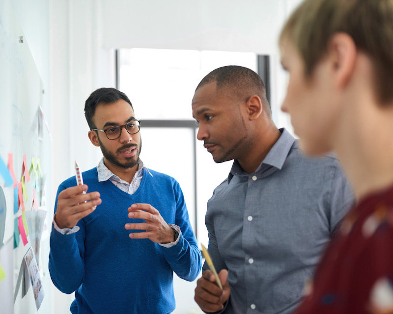 Multi-ethnic group hipster trendy business people with Indian boss discussing during a brainstorm session for their small company