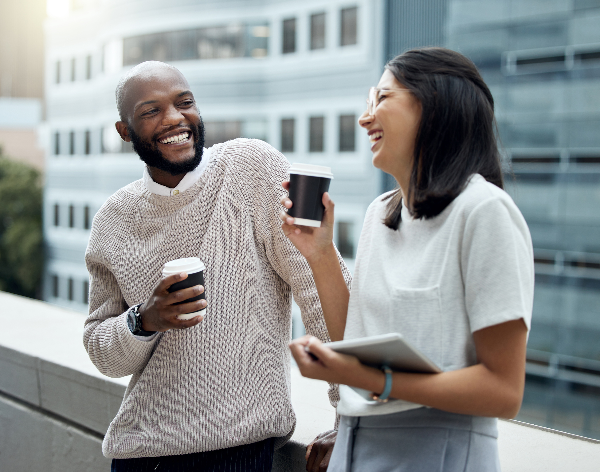 Two businesspeople drinking coffee together outside an office