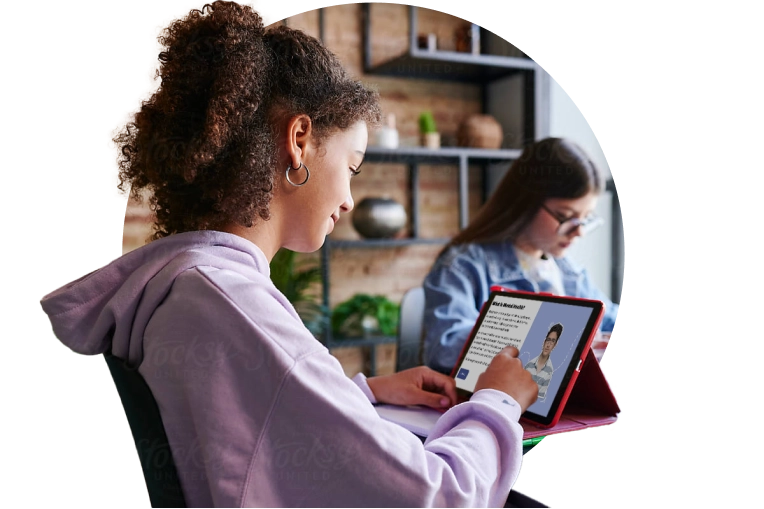 Two young ladies on their electronics sitting at a table